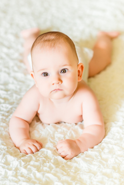 Adorable six months old baby wearing diapers lying on the bed at home - Φωτογραφία, εικόνα