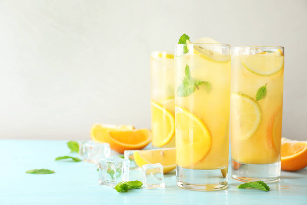 Glasses of citrus refreshing drink on light blue wooden table, space for text - 写真・画像