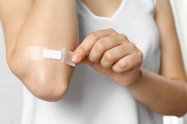 Female applying plaster on elbow against white background, closeup view - Photo, Image