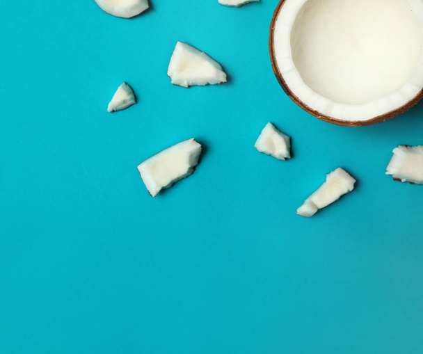Fresh coconut pieces on blue background, flat lay. Space for text - Фото, зображення