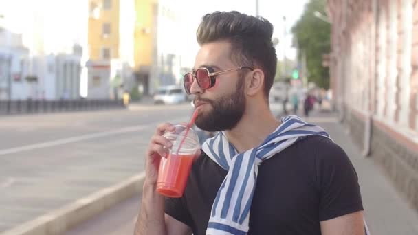 Concepto de comida callejera y vida urbana. Joven hombre barbudo sonriente sosteniendo una taza con batidos de jugo de bebida o limonada
 - Metraje, vídeo