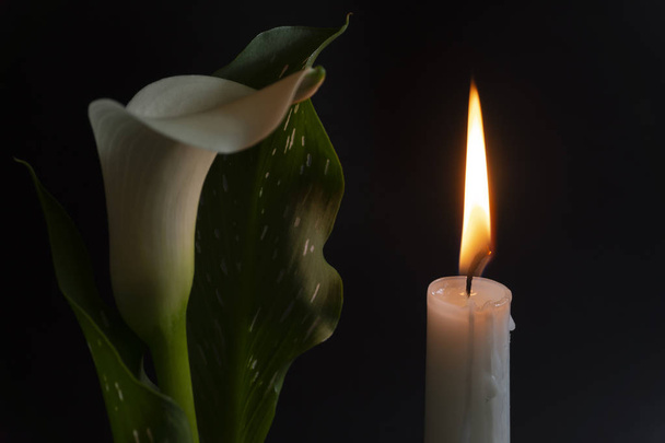 Primer plano de llama de vela naranja y flores de lirio
 - Foto, Imagen