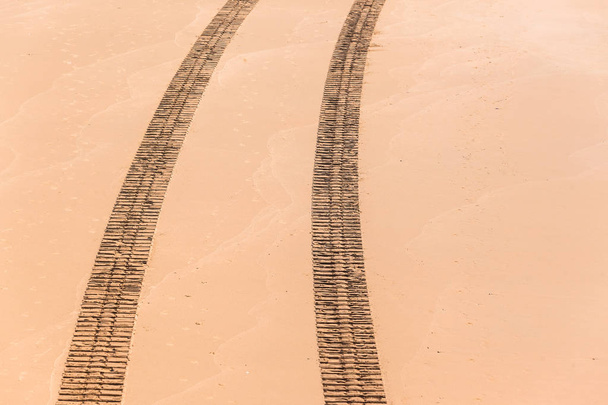 Ajoneuvon jäljet yläpuolisen rannan hiekkaa
 - Valokuva, kuva