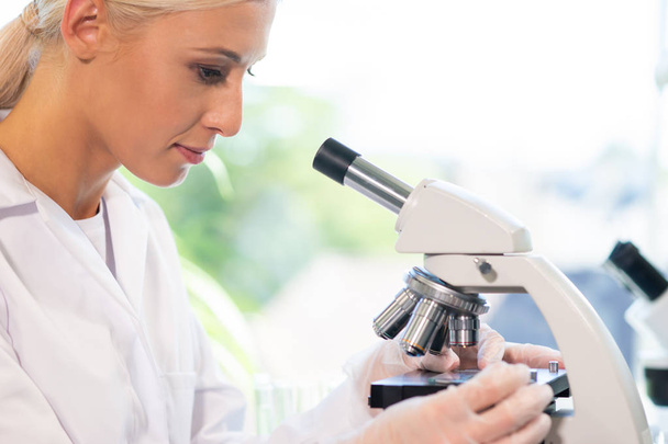 Female scientist working in modern lab. Doctor making microbiology research. Laboratory tools: microscope, test tubes, equipment. Biotechnology, chemistry, bacteriology, virology, dna and health care - Photo, Image