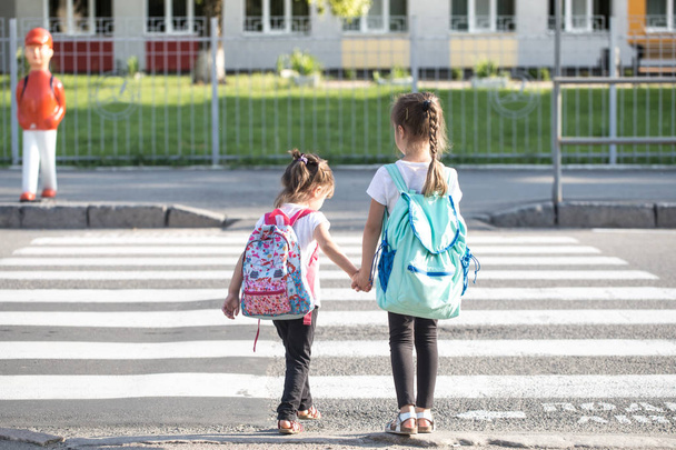 Back to school education concept with girl kids, elementary students, carrying backpacks going to class - Photo, Image