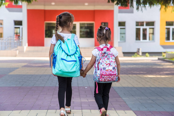 Regreso al concepto de educación escolar con niñas, estudiantes de primaria, llevando mochilas a clase
 - Foto, Imagen