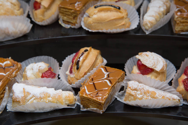 Spousta francouzského dezertu ze profiterolkami dortu ustaránku v cukrárně. Ekler těstoviny Donut na desce. - Fotografie, Obrázek