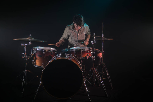 muzikant speelt drums, zwarte achtergrond en mooie zachte licht - Foto, afbeelding