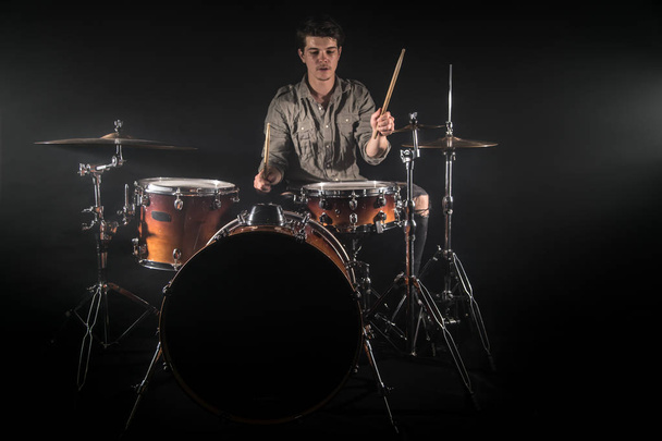 professioneller Schlagzeuger am Schlagzeug auf der Bühne vor schwarzem Hintergrund - Foto, Bild