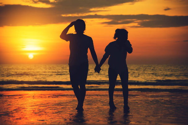 Aasian ystäville pari onnellinen rannalla kaunis auringonlasku taustalla mies nostaa nainen
. - Valokuva, kuva