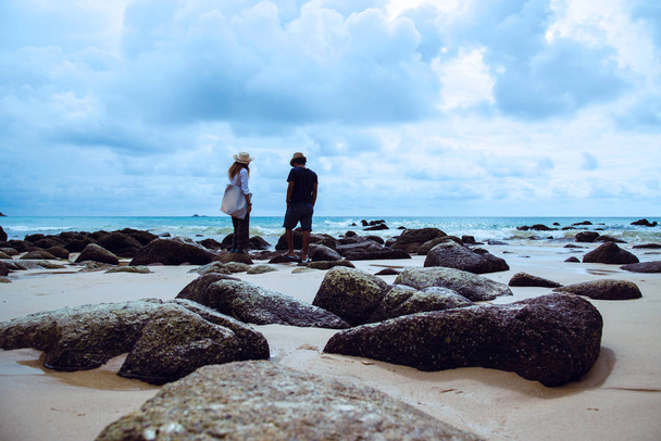 Asian zakochani para szczęśliwy na The plaża. Niebo jest jasne podróże charakter i siedząc odpocząć na skałach na morzu w Phuket. w Tajlandii. Letnich. - Zdjęcie, obraz