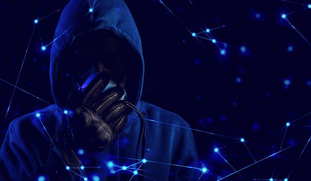 hacker hood outfit and mask with glove on dark background in security virus network and ai hologram robotic concept, data deep learning, server secure hacking - Photo, image