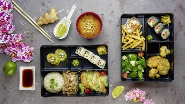 Japanese cuisine. lunch box set, sushi roll, salad, miso, chicken, sauce and wasabi on grey background. - Foto, immagini