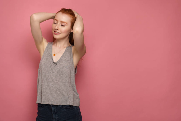 Young redhead girl smoothes her hair with eyes closed - Foto, immagini