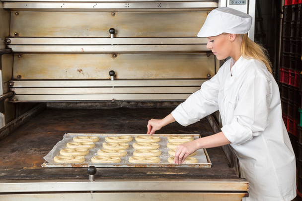 Baker in bakery with baking plate full of pretzels - Photo, Image
