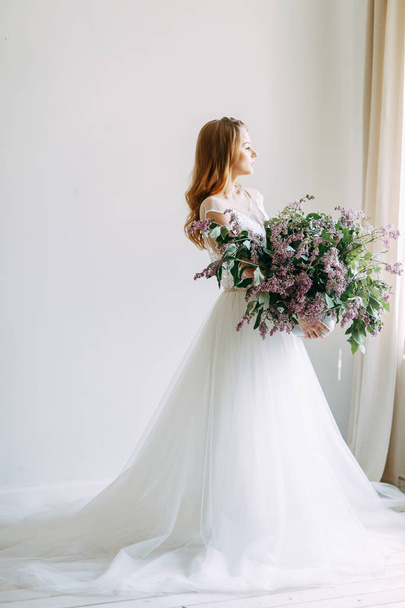  Wedding in European style. Stylish trendy bride in the Studio with a bouquet of lilacs. - Foto, imagen
