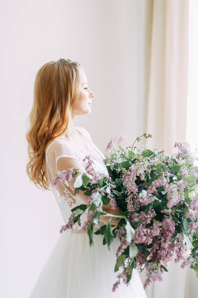  Wedding in European style. Stylish trendy bride in the Studio with a bouquet of lilacs. - Фото, изображение