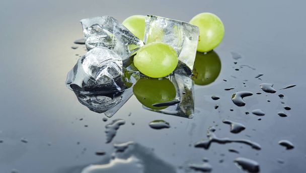 Raisins verts frais avec gouttes d'eau et glace sur fond gris
 - Photo, image