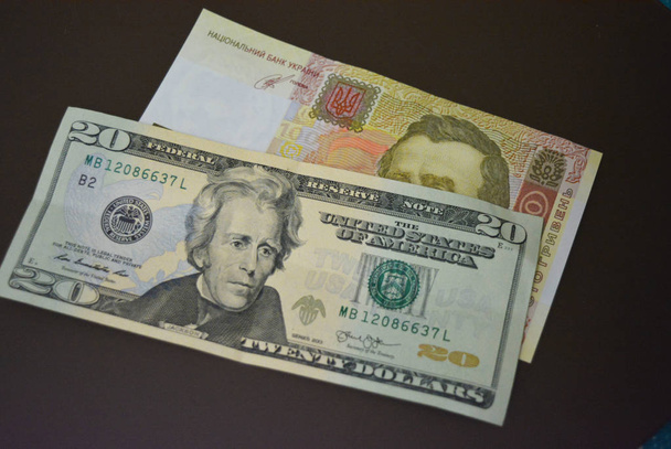 Papír számlák mérete USD $20 húsz amerikai dollár és UAH 100 100 ukrán Hrivnya egy barna Matt háttér. Ukrán és amerikai valuták, fizetések és készpénzfizetések. - Fotó, kép