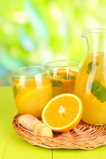 Orange lemonade in pitcher and glasses on wooden table on natural background - Fotó, kép
