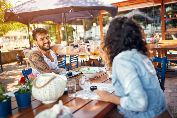 couple sitting in a restaurant enjoying in beer and and conversation - Foto, imagen