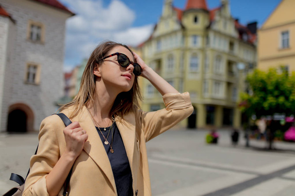 Woman in sunglasses and backpack in aged city center square. Poland - Photo, Image