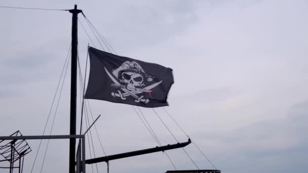 Merirosvolippu Jolly Roger roikkuu laivan mastossa sinisen taivaan taustalla tuulisena päivänä
. - Materiaali, video