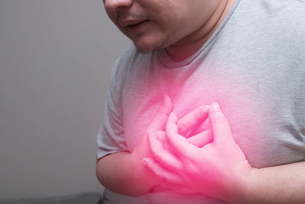  Tłuszczowych człowieka z czerwonym miejscu w klatce piersiowej, ponieważ silny ból serca, cierpiących na bóle w klatce piersiowej, zawał serca - Zdjęcie, obraz