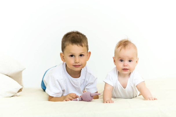 Portrait of brother and sister. Two cute children lying on bed - Fotoğraf, Görsel