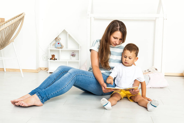 Mother Sitting With Son Reading Story Indoors - Photo, Image