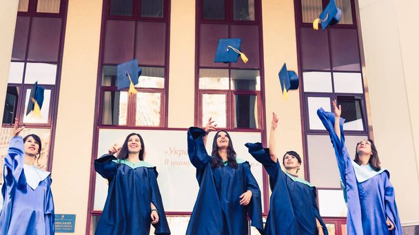 Üniversite mezunları mezuniyet şapkalarını havaya atıyorlar. Grup - Fotoğraf, Görsel