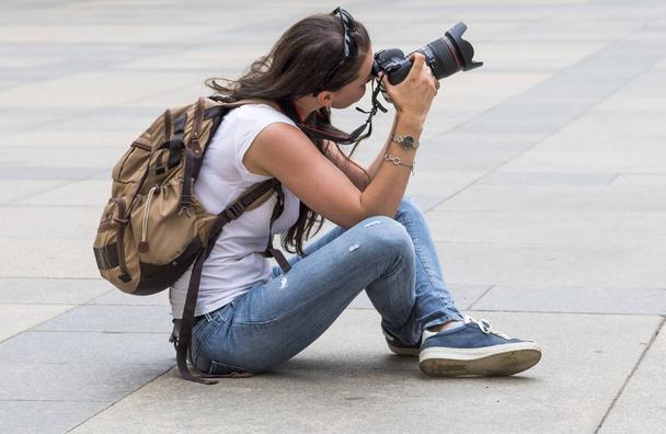 Woman traveler and photographer sitting on the street countryside. - Zdjęcie, obraz