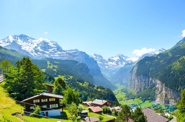 Γραφικό αλπικού χωριού Βένγκεν, Ελβετία. Οι διάσημοι και οι καταρράκτες Στάμπμπαχ στο παρασκήνιο. Ελβετικές Άλπεις με χιόνι από πάνω. Ελβετία το καλοκαίρι. Αλπικό τοπίο - Φωτογραφία, εικόνα