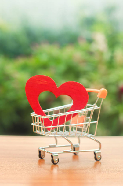 Red wooden heart in the trading cart. concept of buying love. nature background. Health care and purchase of medicines. Health care budget. Love for shopping. Favorite store. Buy love and happiness. - Фото, зображення