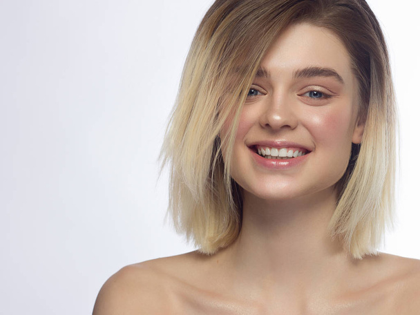 Close-up portrait of a beautiful woman smiling at the camera. Short haircut and natural makeup. Happy smile with white teeth. Spa and cosmetology, dentistry - Photo, Image