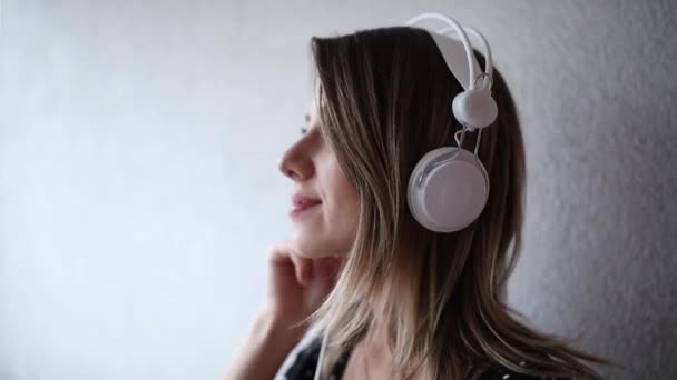 kobieta ze słuchawkami i okulary przeciwsłoneczne na tle muru ceglanego - Materiał filmowy, wideo