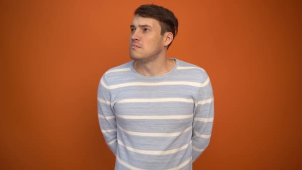 Sad handsome man received a gift and began to dance happily on an orange background. Holiday concept, holiday discounts, gifts and sales. - Footage, Video