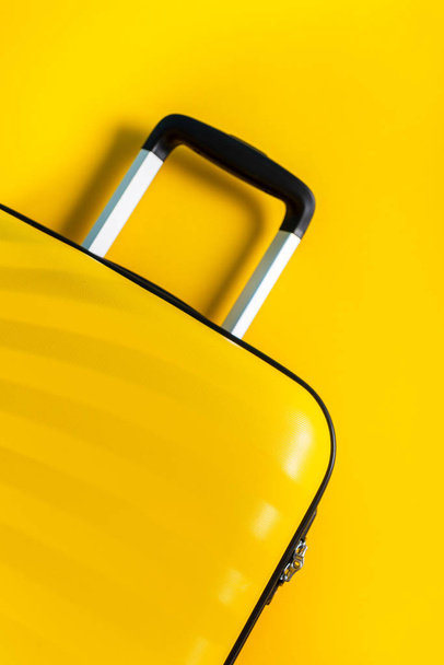 Φωτεινή και κομψή βαλίτσα σε μέγεθος καμπίνας σε φωτεινό κίτρινο φόντο - Φωτογραφία, εικόνα