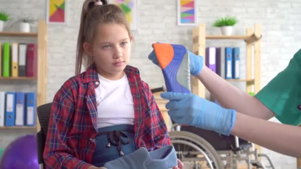 Lekarz ortopedyczny opowiada nastoletnią dziewczynę o podeszwach ortopedycznych z bliska - Materiał filmowy, wideo