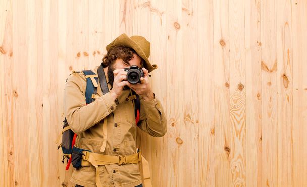 young crazy explorer with straw hat and backpack on wood background - Foto, Bild