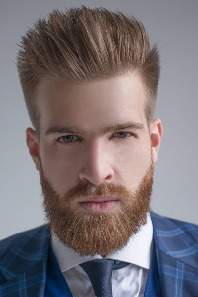 Close up of stylish handsome bearded businessman looking at camera isolated on grey - Fotó, kép