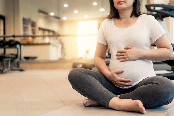 Actieve zwangere vrouw oefening in fitnesscentrum. - Foto, afbeelding