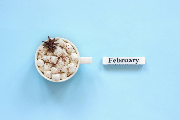 Cup of cocoa marshmallows and calendar February on blue background - Φωτογραφία, εικόνα