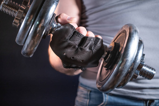 Strong man in sporty gloves with dumbbell - Foto, afbeelding