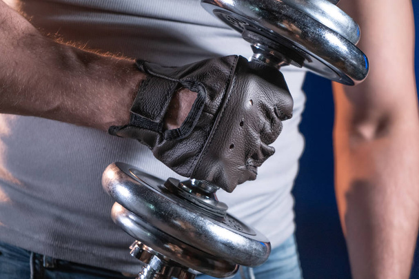 Strong man in sporty gloves holding dumbbell - Φωτογραφία, εικόνα