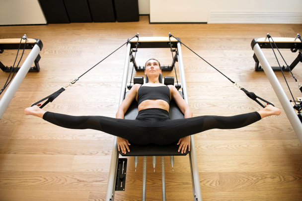 Woman on reformer bed doing hip opening exercises - Foto, immagini