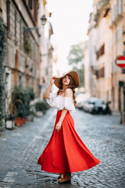 Portrait of a girl in a red dress and hat. Stylish bride on the streets of Rome.  - Fotoğraf, Görsel
