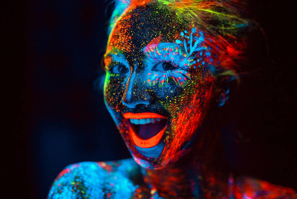 Portrait of a girl painted in fluorescent powder - 写真・画像