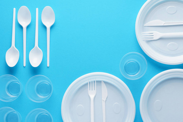 White plastic disposable tableware on blue background. - Фото, изображение