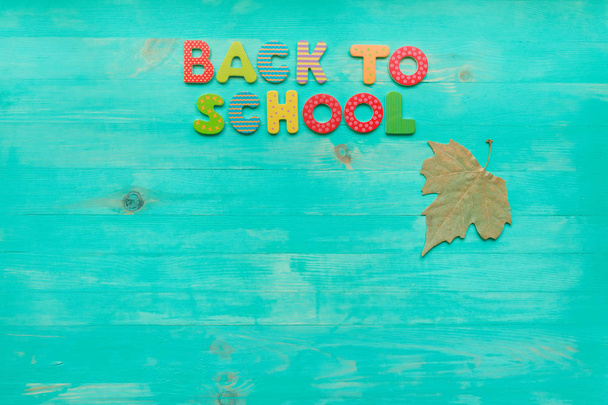 Back to school concept. Top view of colorful text and autumn dry leaf banner over wooden background with copy space. - Photo, Image
